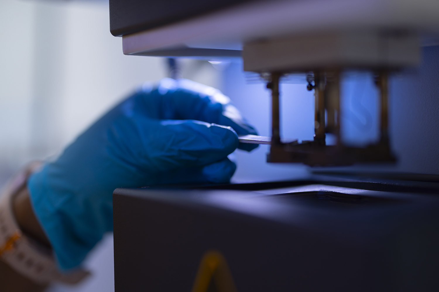 A gloved hand loading a sample in the DMA.