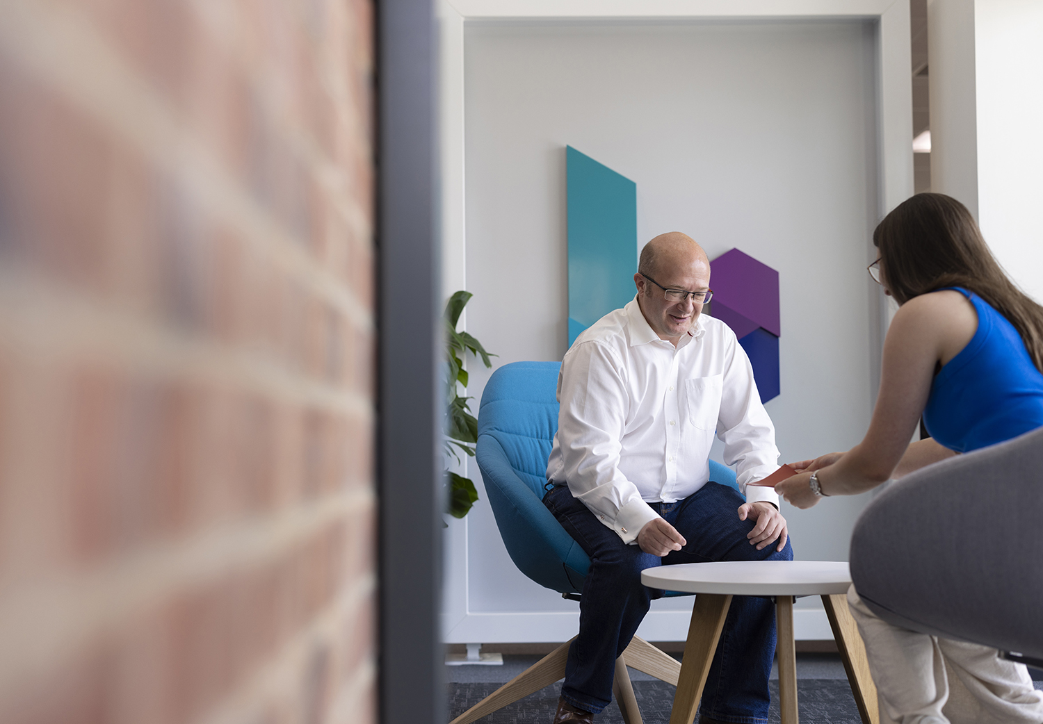 A smiling man in a white shirt sat in a blue chair