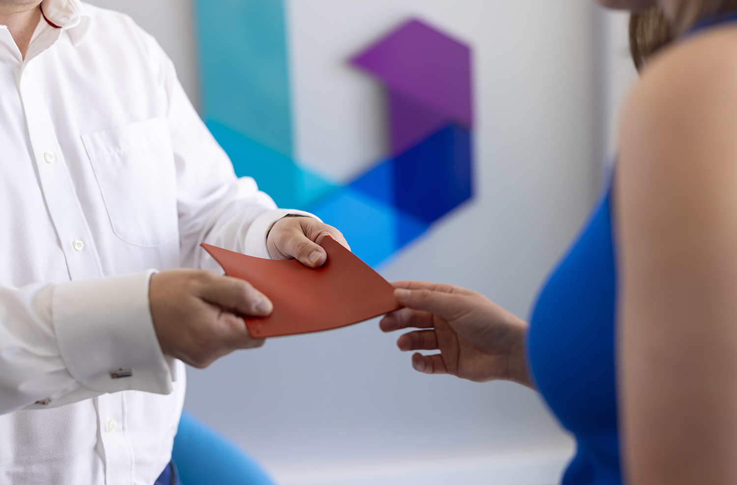 Man passing a sample ot terracotta coloured rubber to a woman