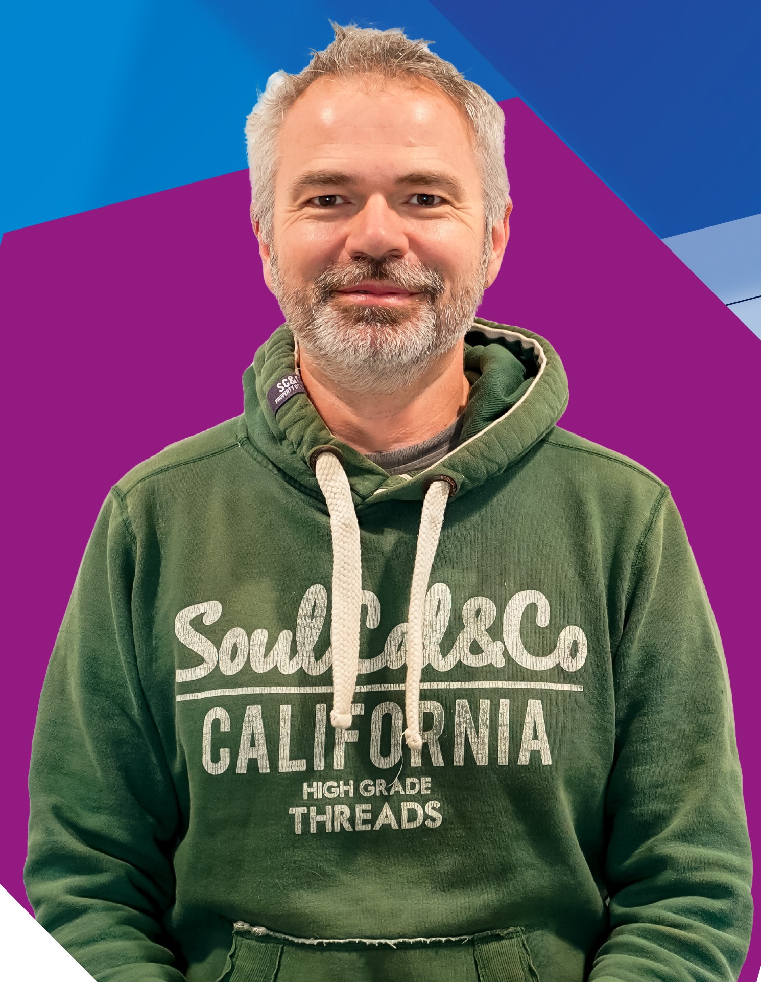 A smiling man wearing a green hoody